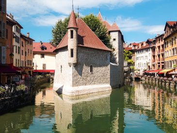 white and brown concrete building beside river under blue sky during daytime